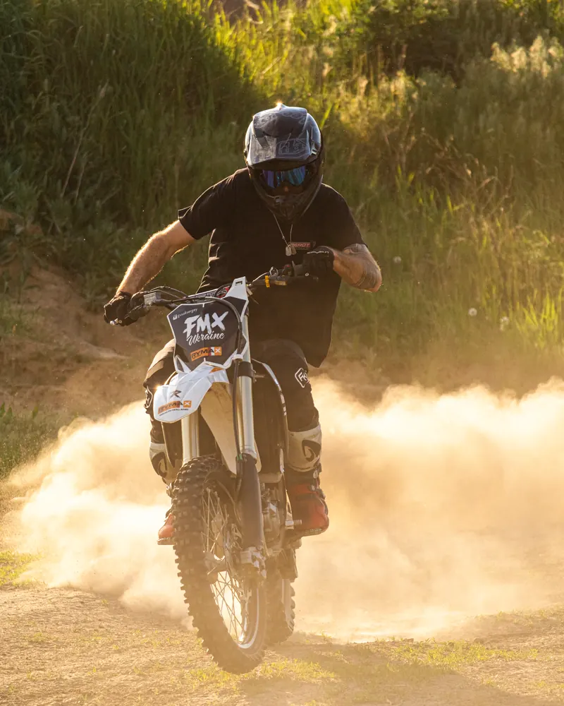 A dirt bike rider kicking up a cloud of dust on a dirt track