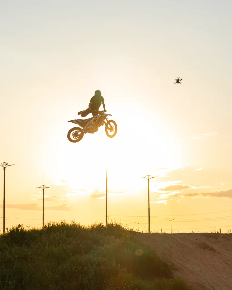Silhouette of a motocross rider performing a jump against a sunset sky.